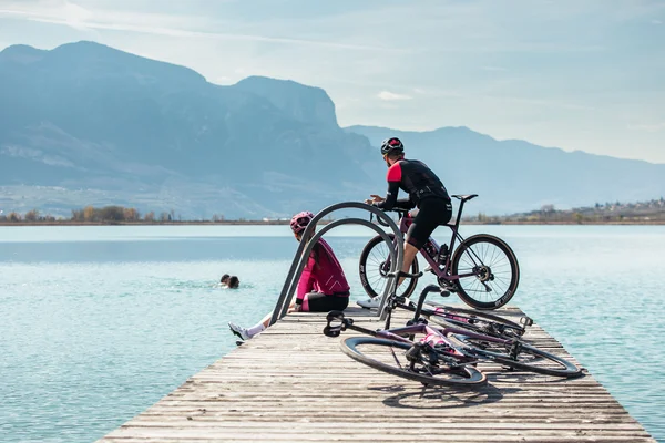 Italien © TV Kaltern am See - Felix Homann Zwei Radfahrer auf Steg am See mit Bergen im Hintergrund