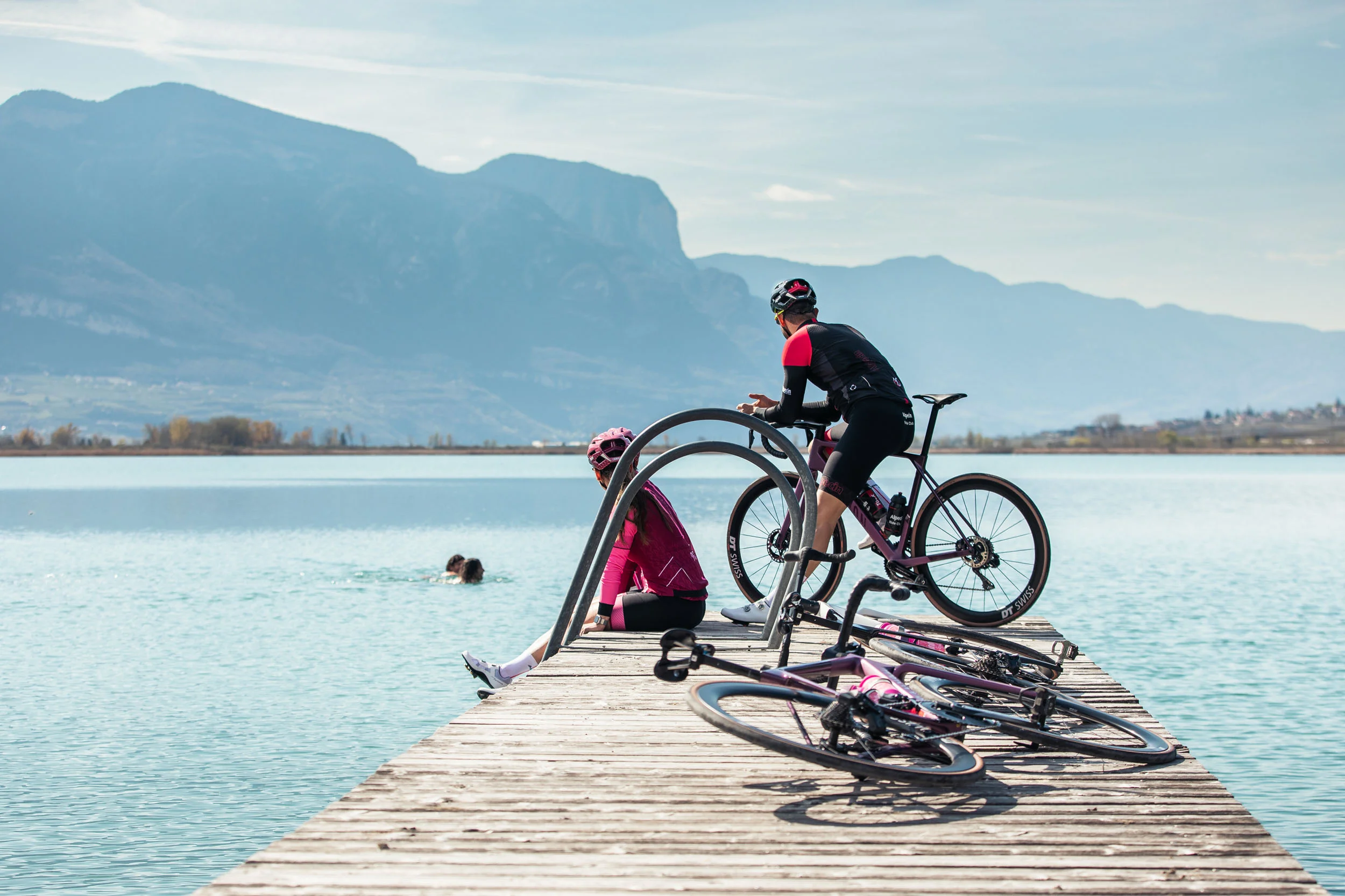 Italien © TV Kaltern am See - Felix Homann Zwei Radfahrer auf Steg am See mit Bergen im Hintergrund
