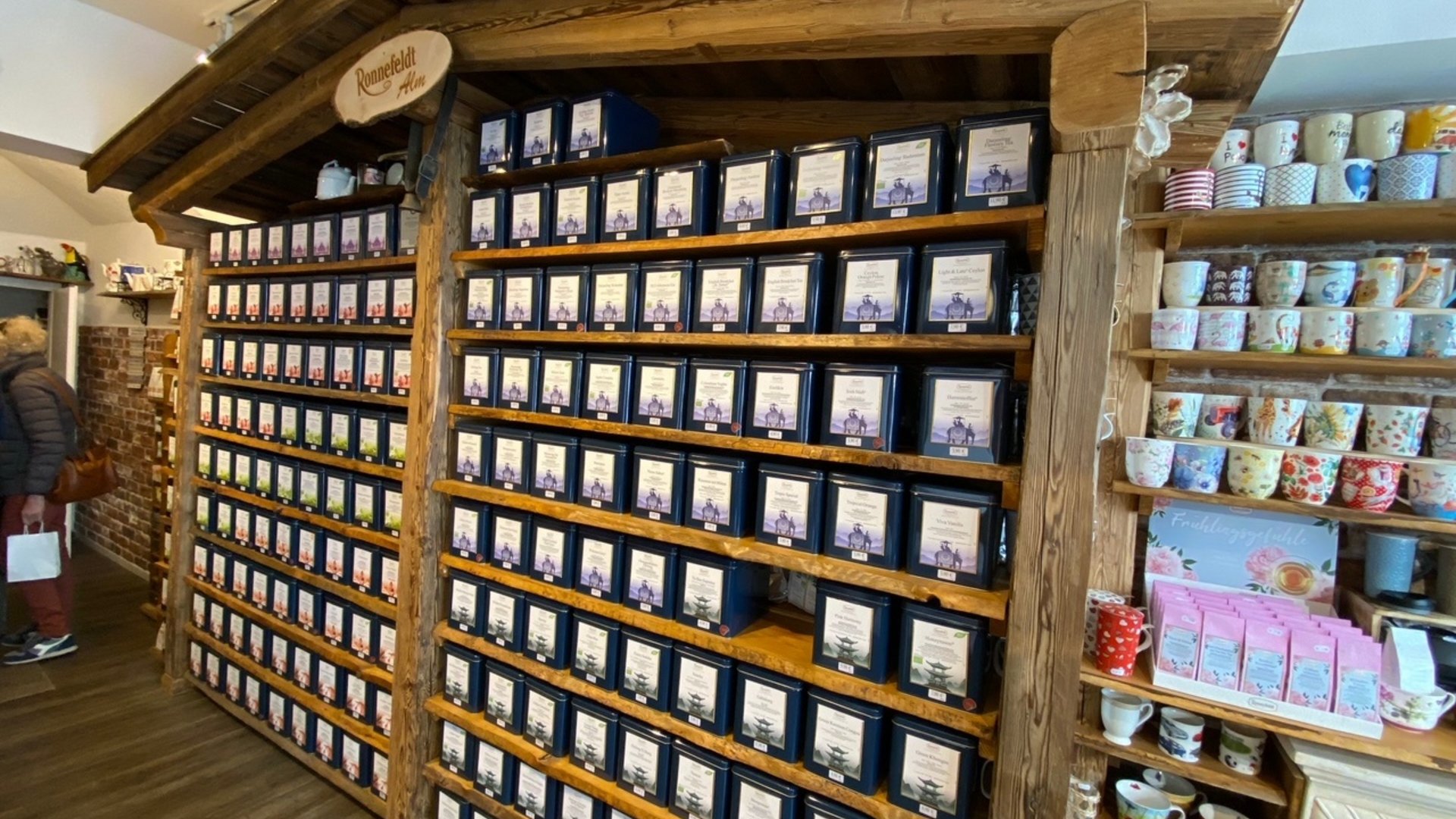 Shelf with many tea tins and colorful mugs in a tea shop