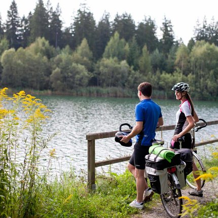 Zwei Radfahrer stehen am Seeufer und genießen die Aussicht