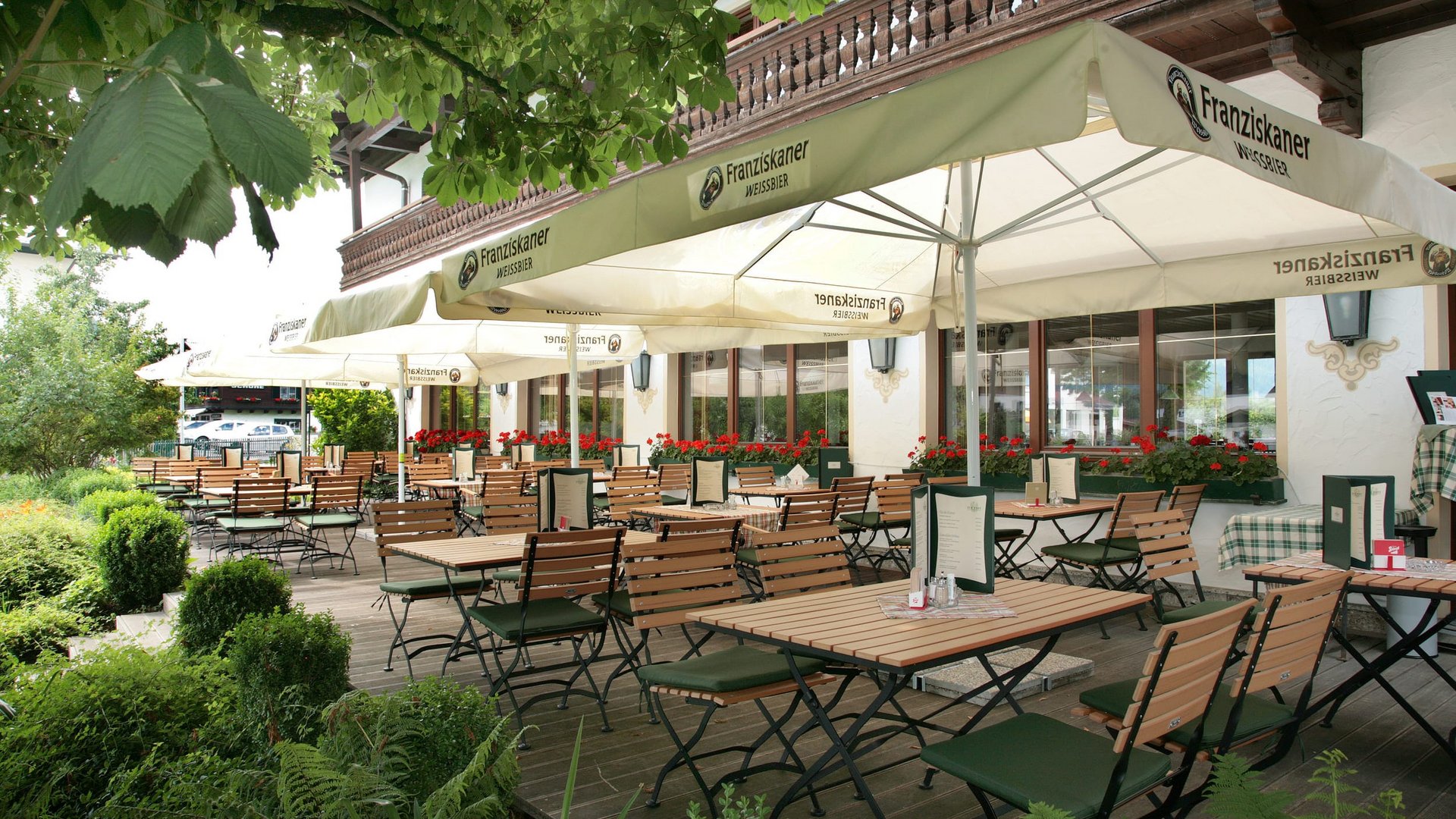 Empty café terrace with wooden tables and umbrellas in a green garden