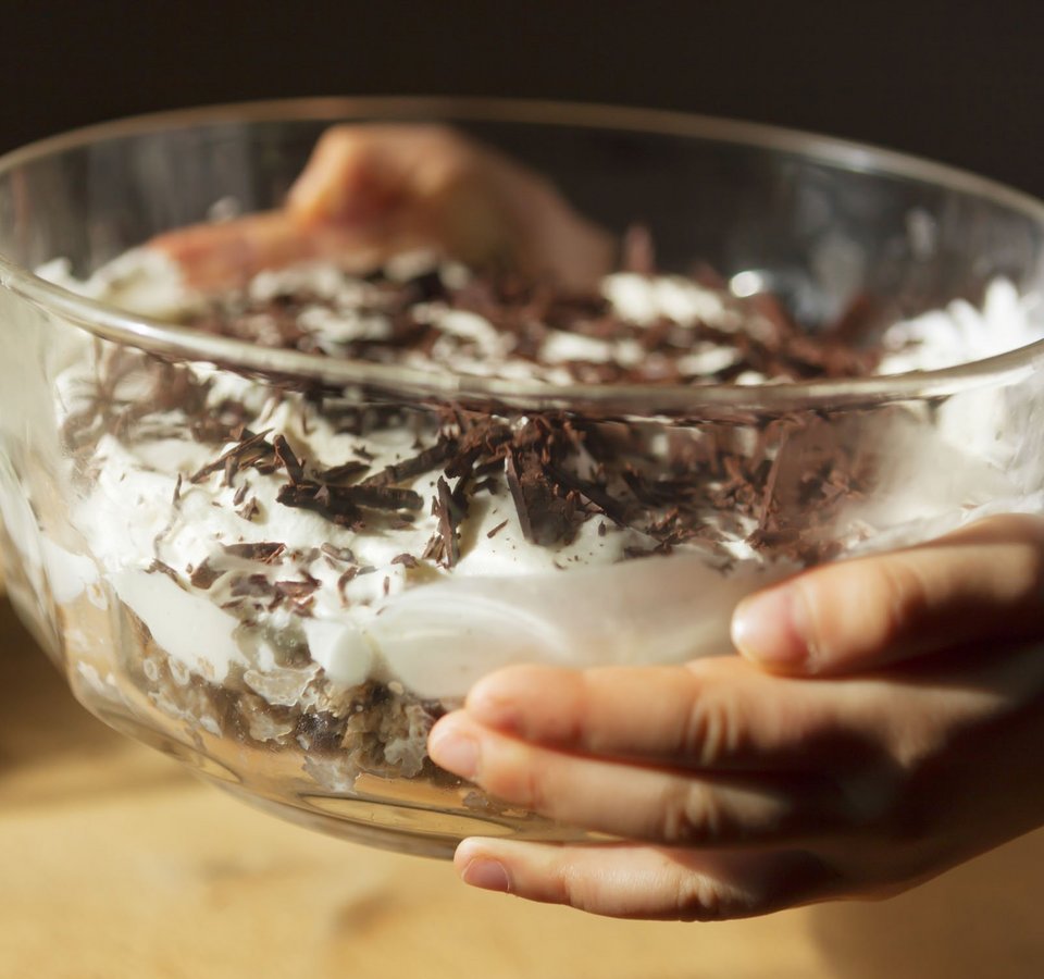 Child holding bowl with whipped cream and chocolate shavings dessert