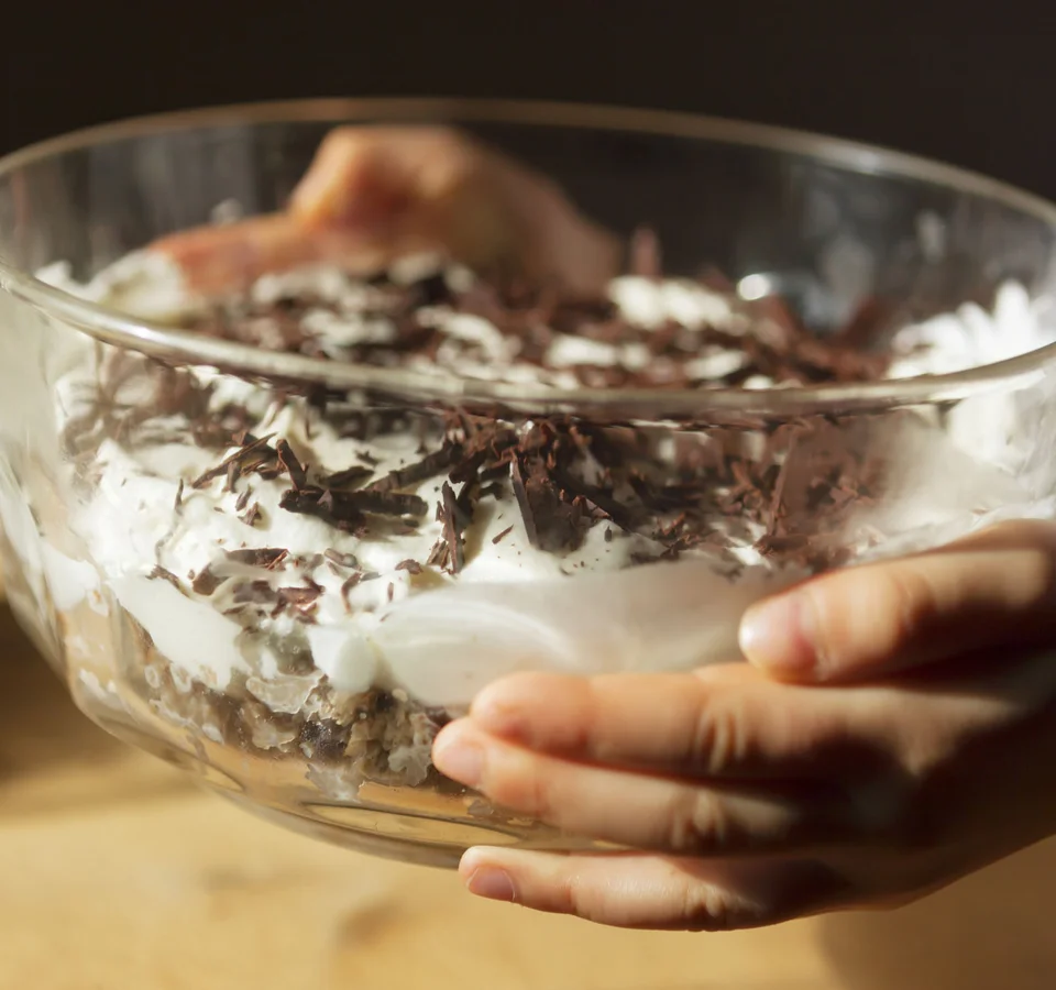 Kind houdt kom met dessert van slagroom en chocoladeschilfers vast