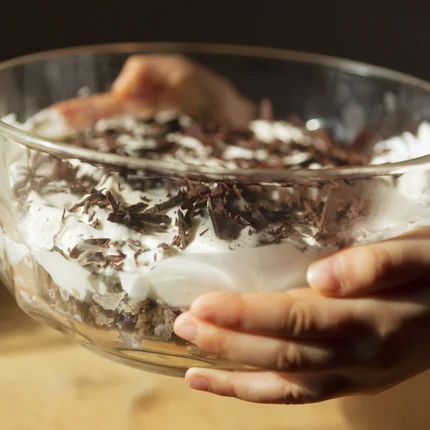 Kind houdt kom met dessert van slagroom en chocoladeschilfers vast