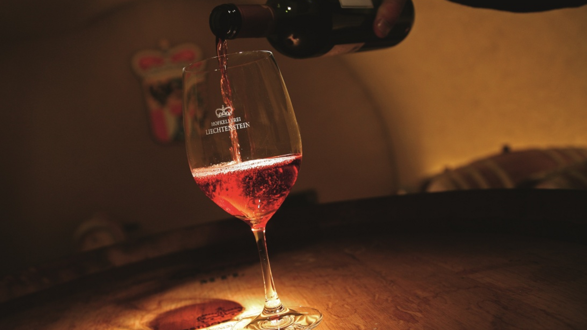Red wine being poured into a wine glass in a cellar
