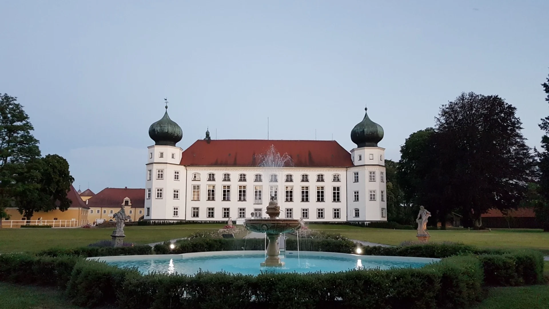 Schloss mit zwei Kuppeltürmen und Springbrunnen im Garten