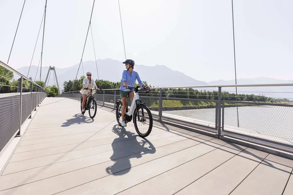 Liechtenstein © Christoph Schöch Twee vrouwen fietsen over een brug op een zonnige dag