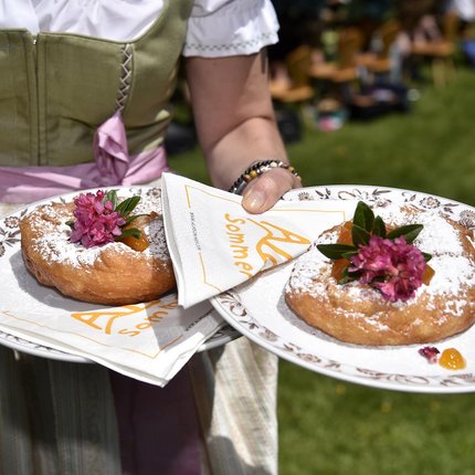 Person holding plates with traditional cake topped with powdered sugar and flower