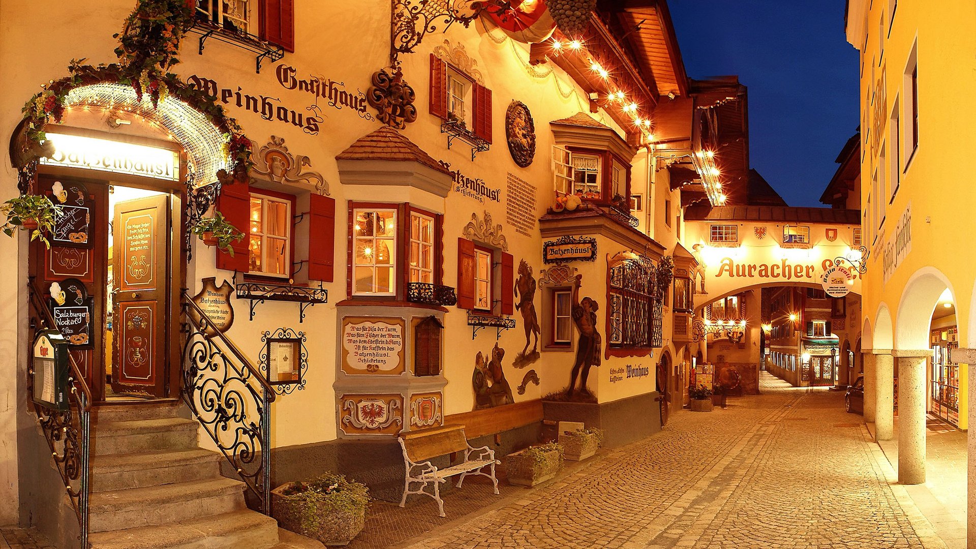 Lit street with traditional guesthouse facades at night