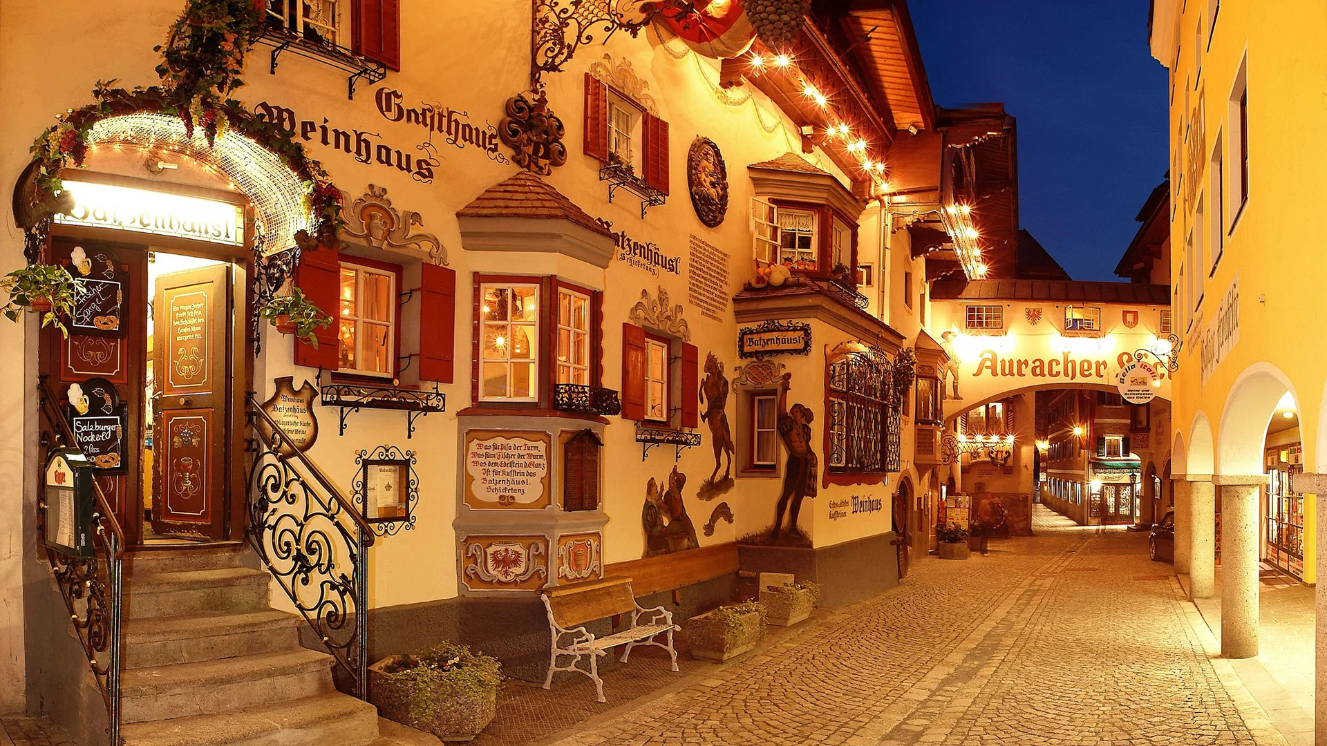 Lit street with traditional guesthouse facades at night