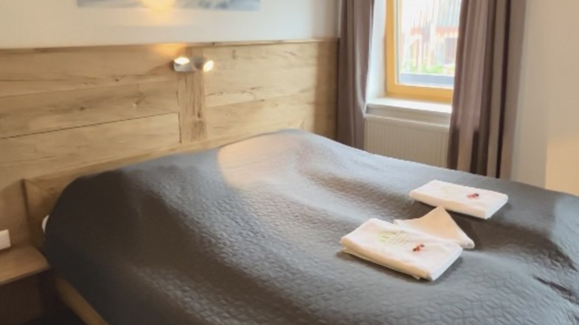 Cozy bedroom with wooden bed, gray bedspread, and window with curtains