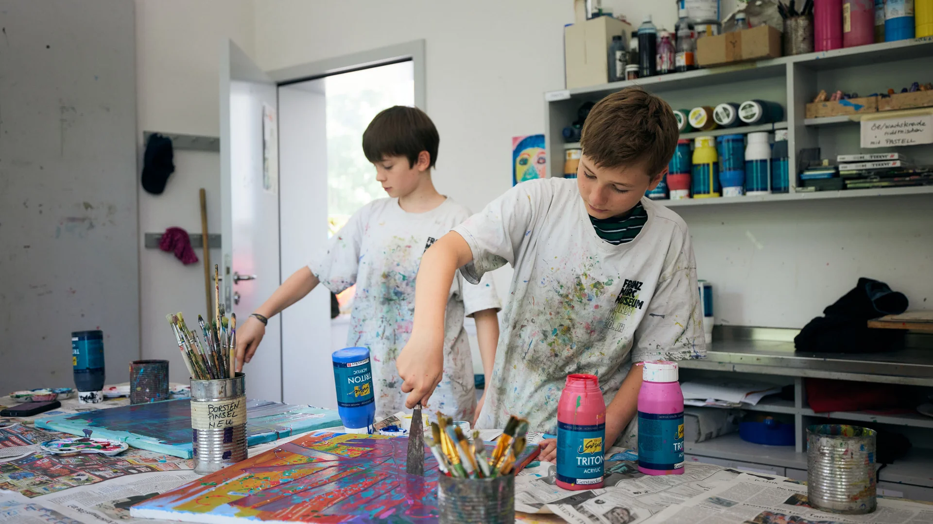 Twee jongens schilderen creatief met kleurrijke verf in een atelier
