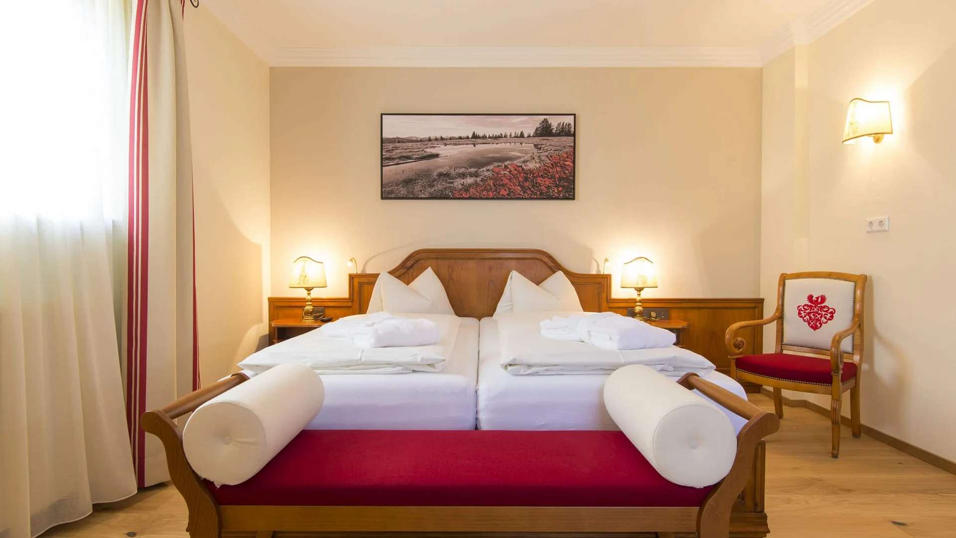 Cozy hotel room with two single beds and a red upholstered bench
