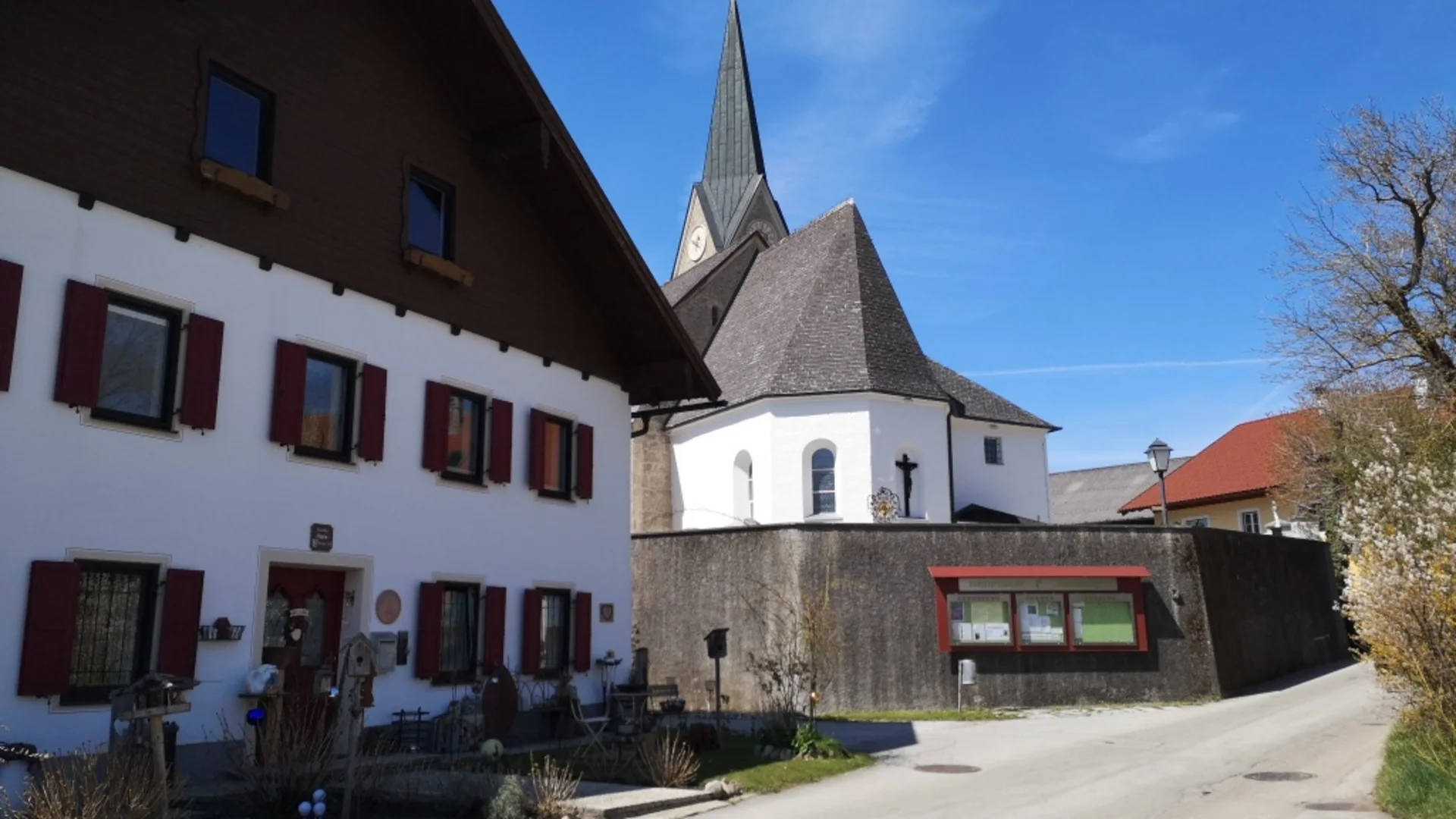 Tour-Detail © Bettina Bauer Straße mit weißem Haus und Kirche mit hohem Turm unter blauem Himmel