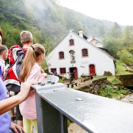 Happy family on a bridge by a house near a river in the forest