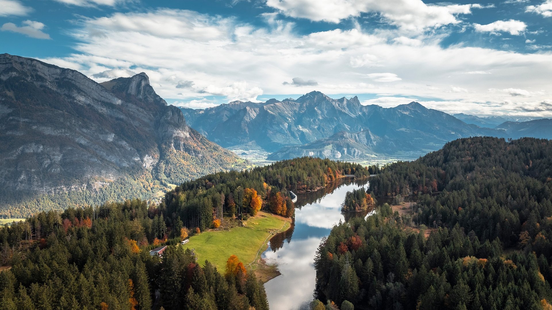 Autumn mountain landscape with river and forested hills under cloudy sky