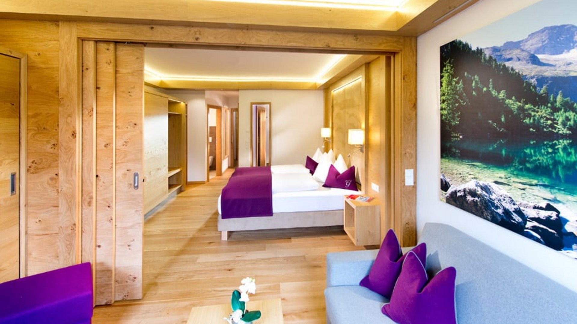 Modern hotel room with wood accents, purple pillows, and large landscape painting