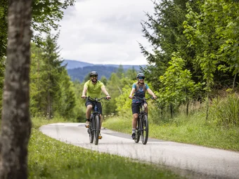 Murtal adventure region © Velontour - Heiko Mandl Two cyclists riding on a rural road through a green forest