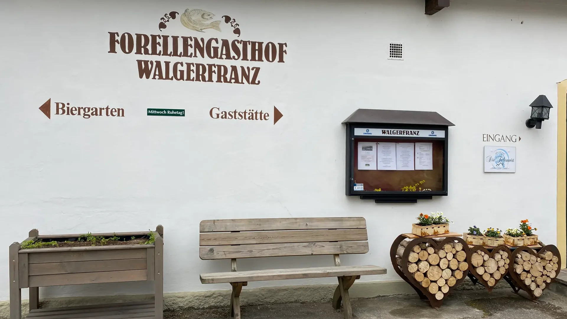 Außenbereich des Forellengasthof Walgerfranz mit Bank und Holzdeko