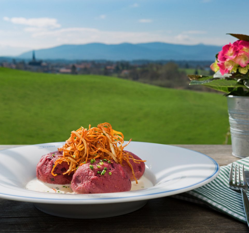 Red dumplings with crispy potato straws on a plate outdoors