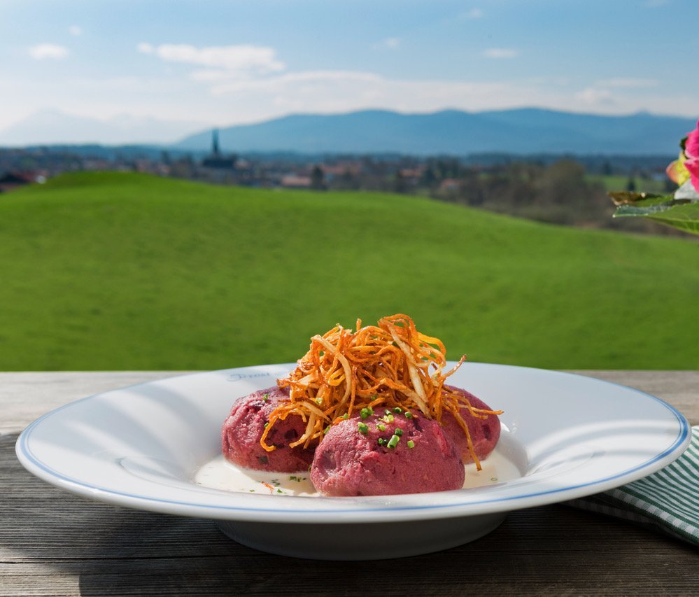 Red dumplings with crispy potato straws on a plate outdoors