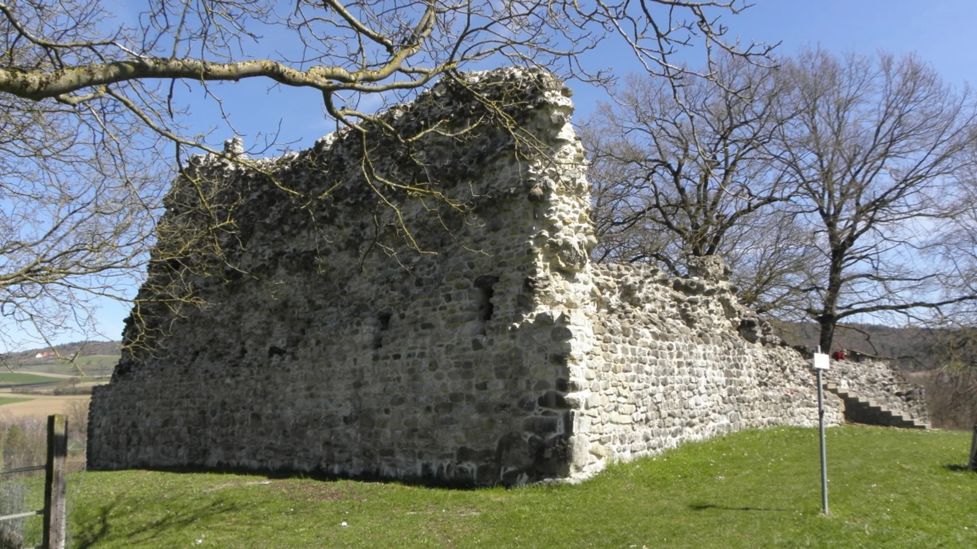 Tour detail © Walter Biselli Ruins of an old stone wall surrounded by trees and blue sky