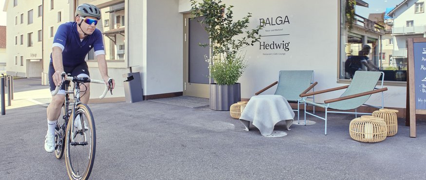 Man riding bicycle past Hedwig restaurant with outdoor seating area