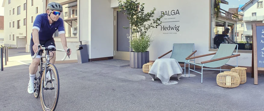 Man riding bicycle past Hedwig restaurant with outdoor seating area