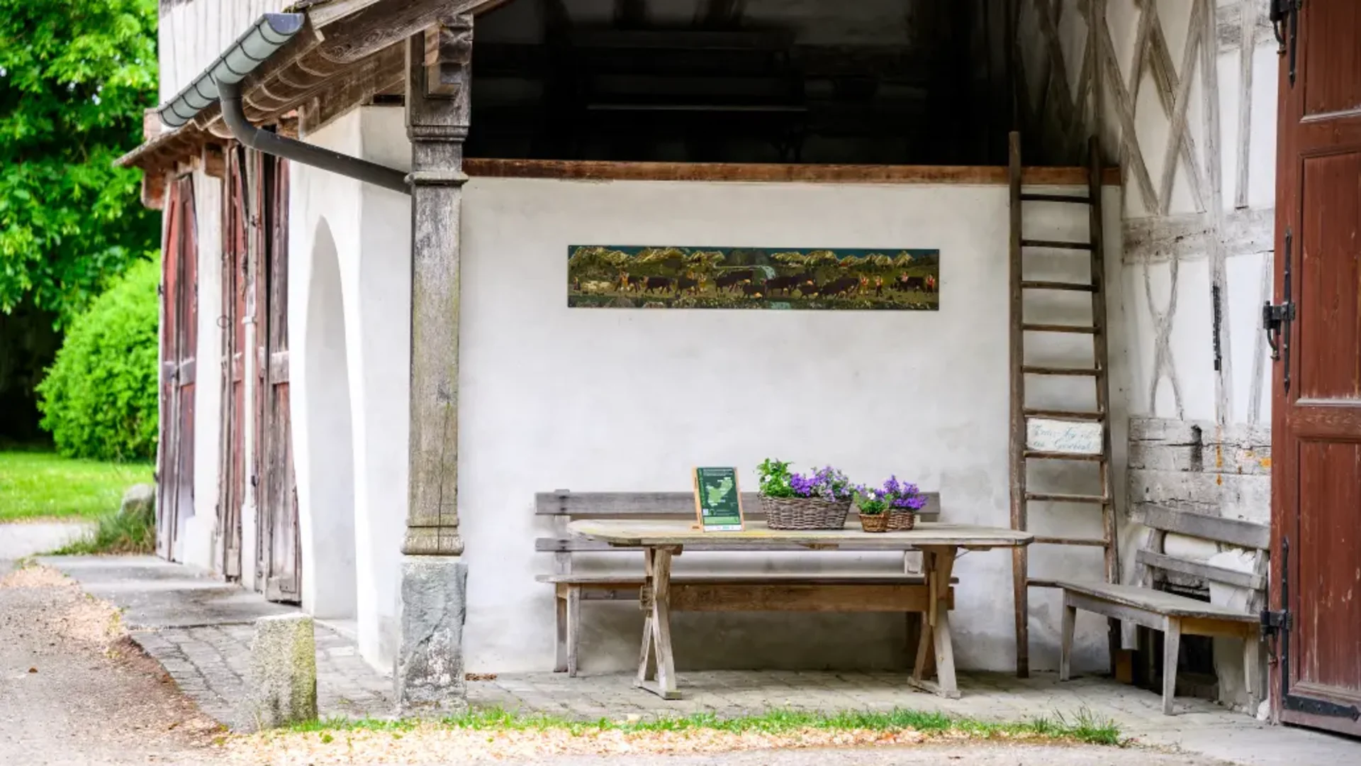 Tour-Detail © Balz Kubli Rustikaler Holztisch mit Blumen unter dem Vordach eines Fachwerkhauses