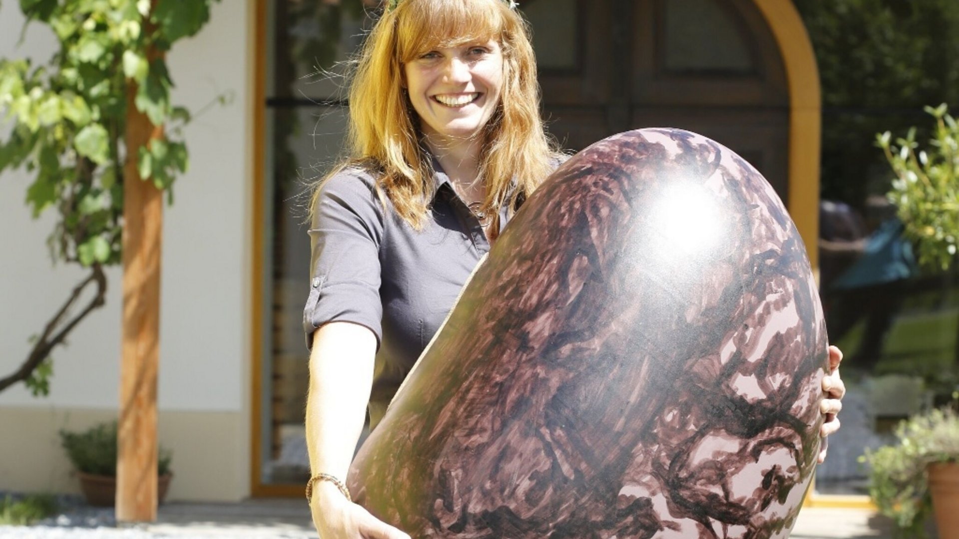 Woman holding large decorated Easter egg outdoors