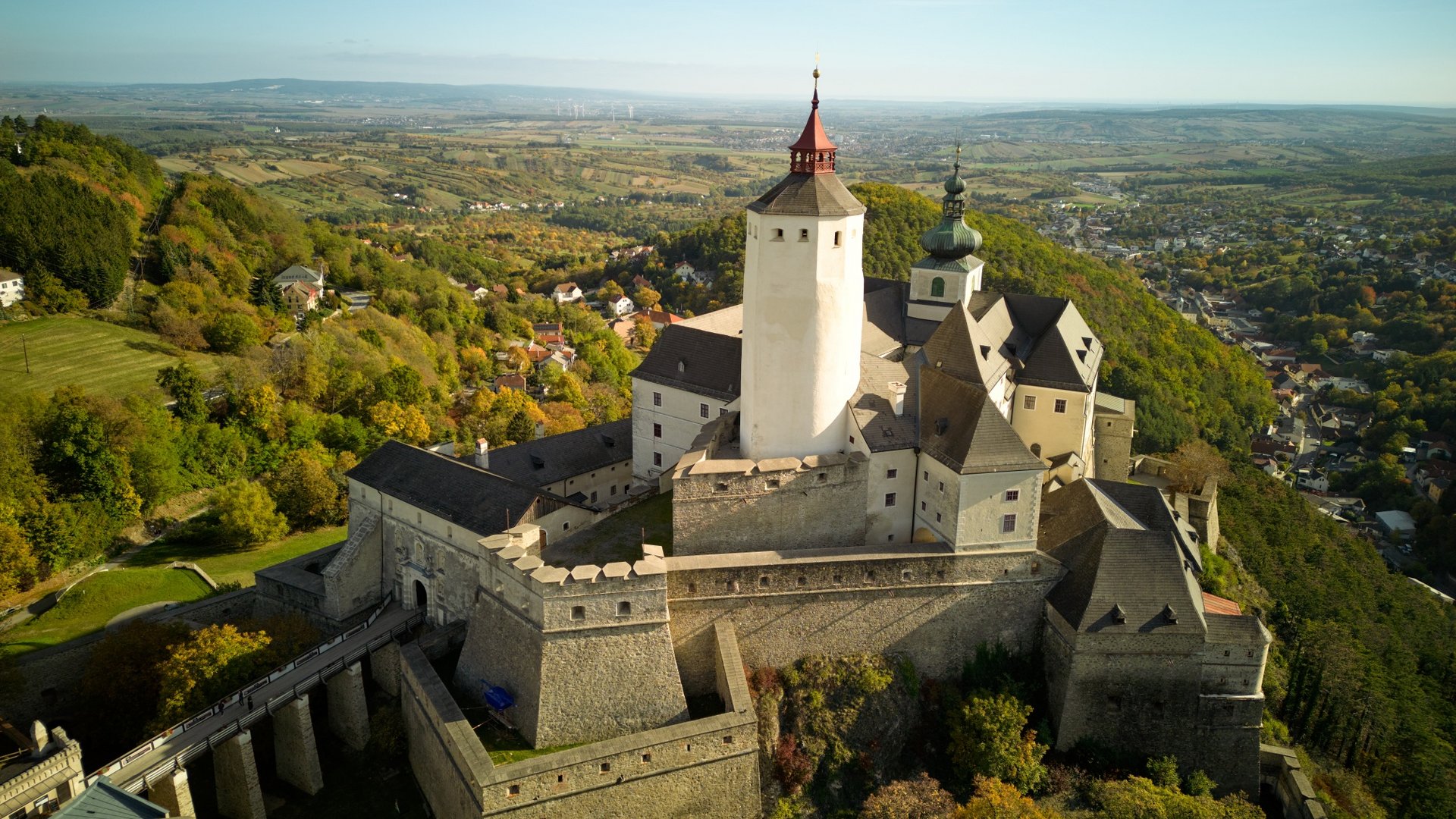 Aerial view of an old castle on a wooded hill under clear sky