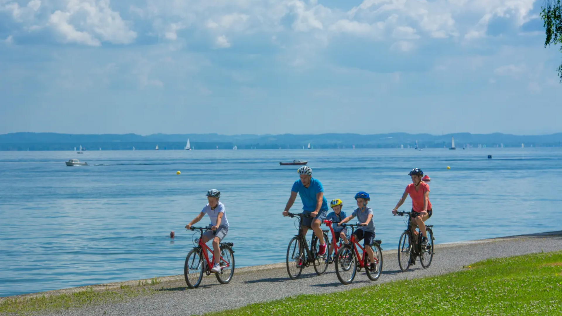 Family biking along a lakeside path on a sunny day
