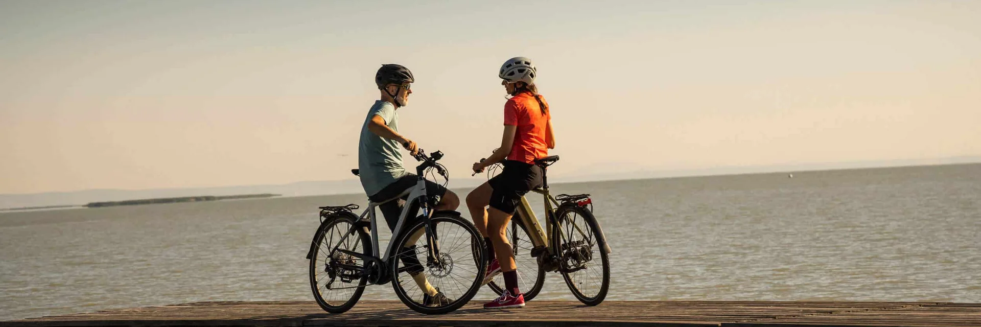 Zwei Radfahrer auf einem Steg über dem Wasser bei Sonnenuntergang