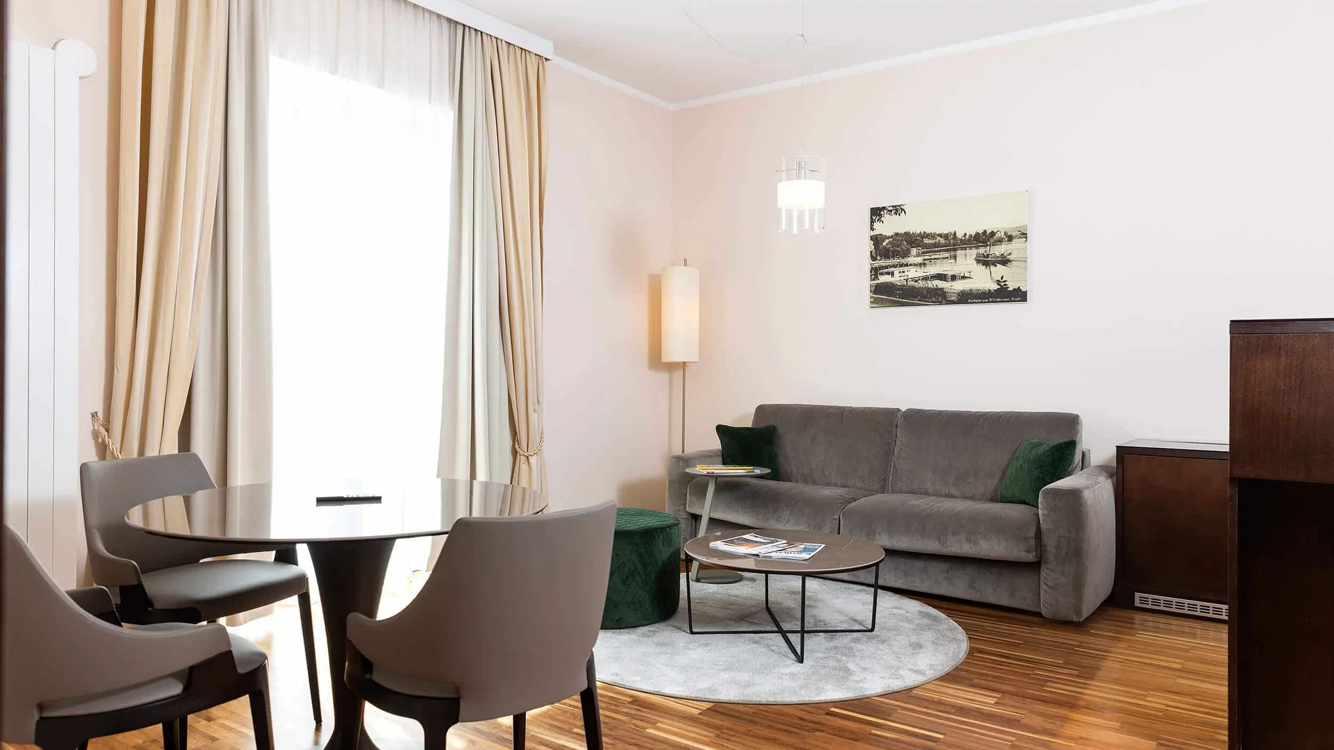 Modern ingerichte woonkamer met bank, stoelen, tafel en groot raam met gordijnen