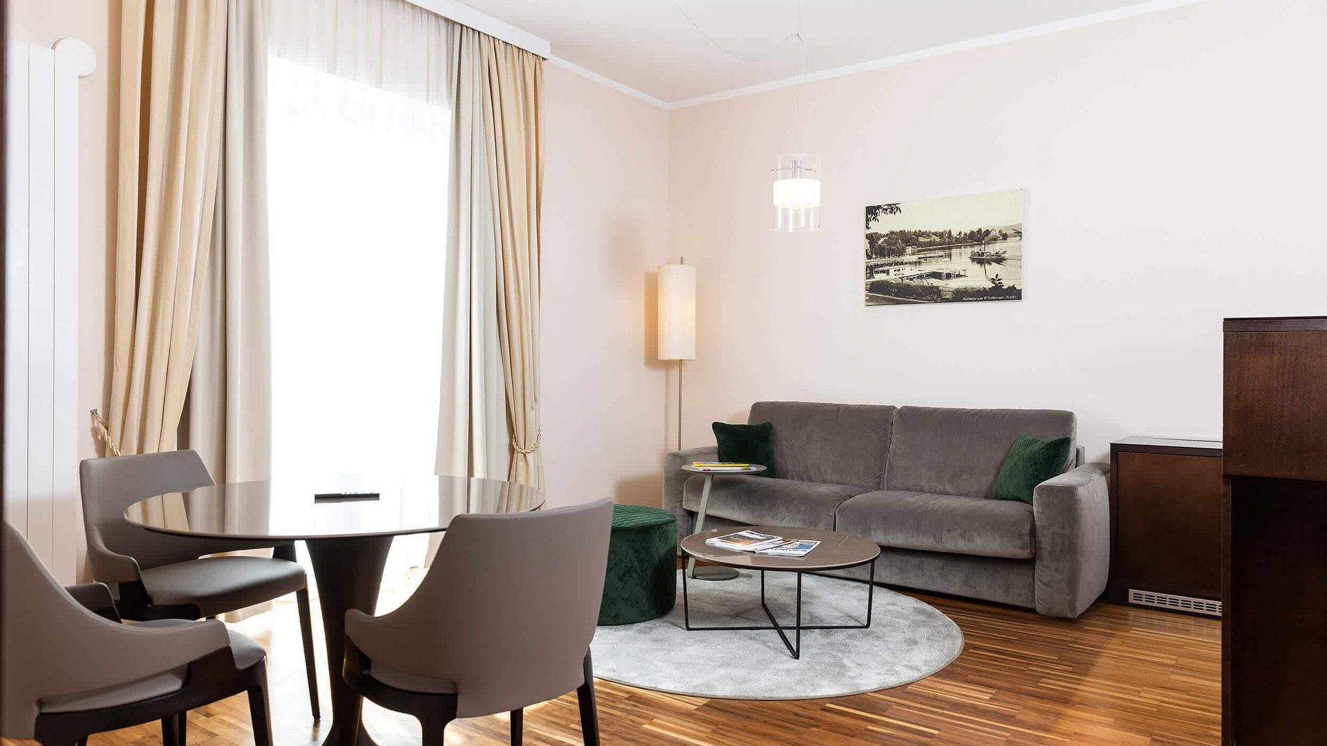 Modern living room with sofa, chairs, table, and large curtained window