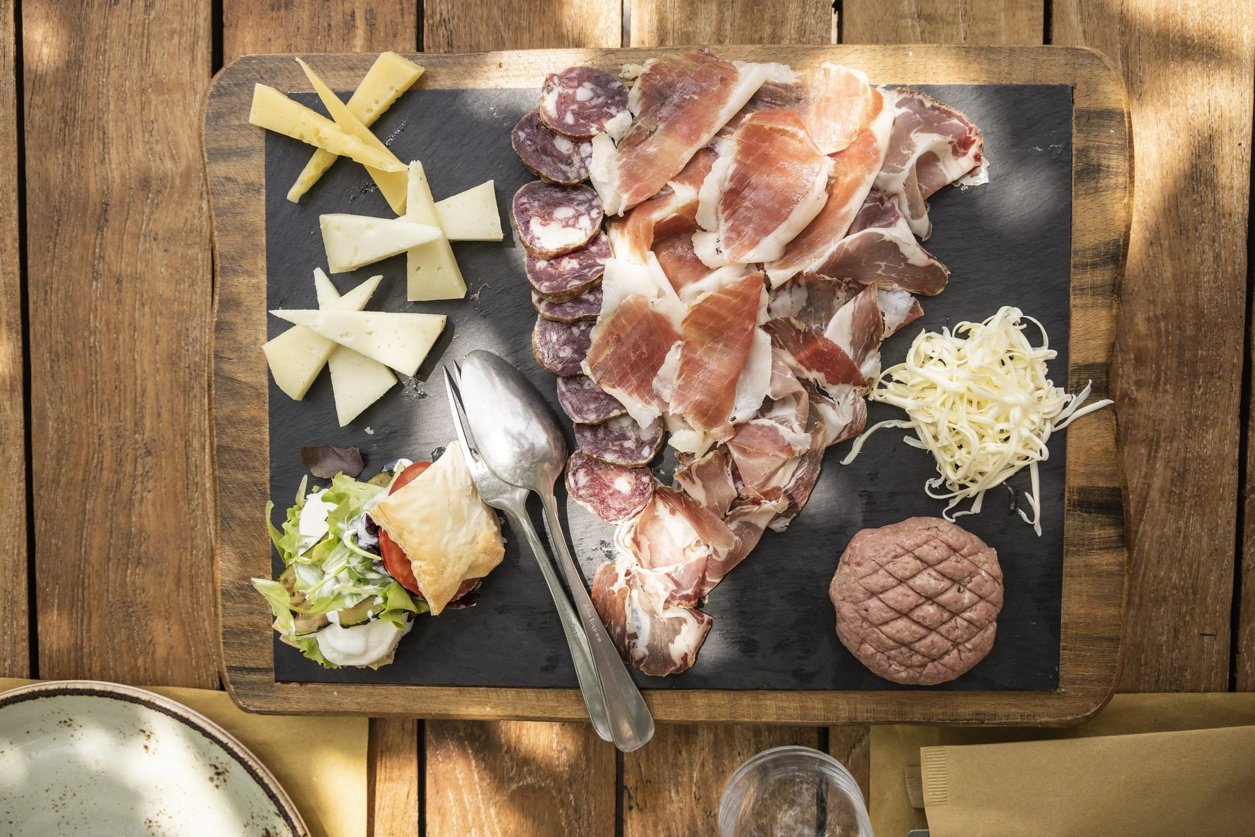 Holzbrett mit verschiedenen Käsesorten, Aufschnitt und Salat