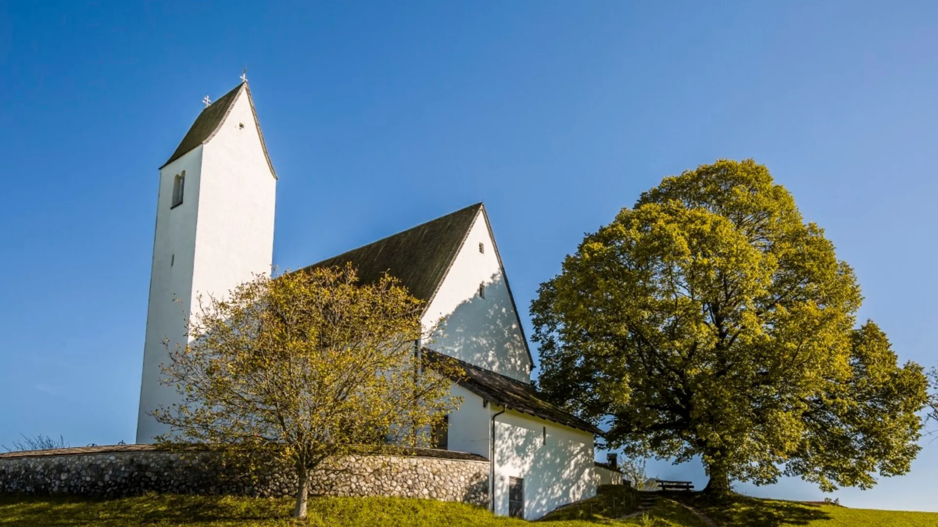Weiße Kirche mit Turm auf grüner Wiese bei klarem Himmel