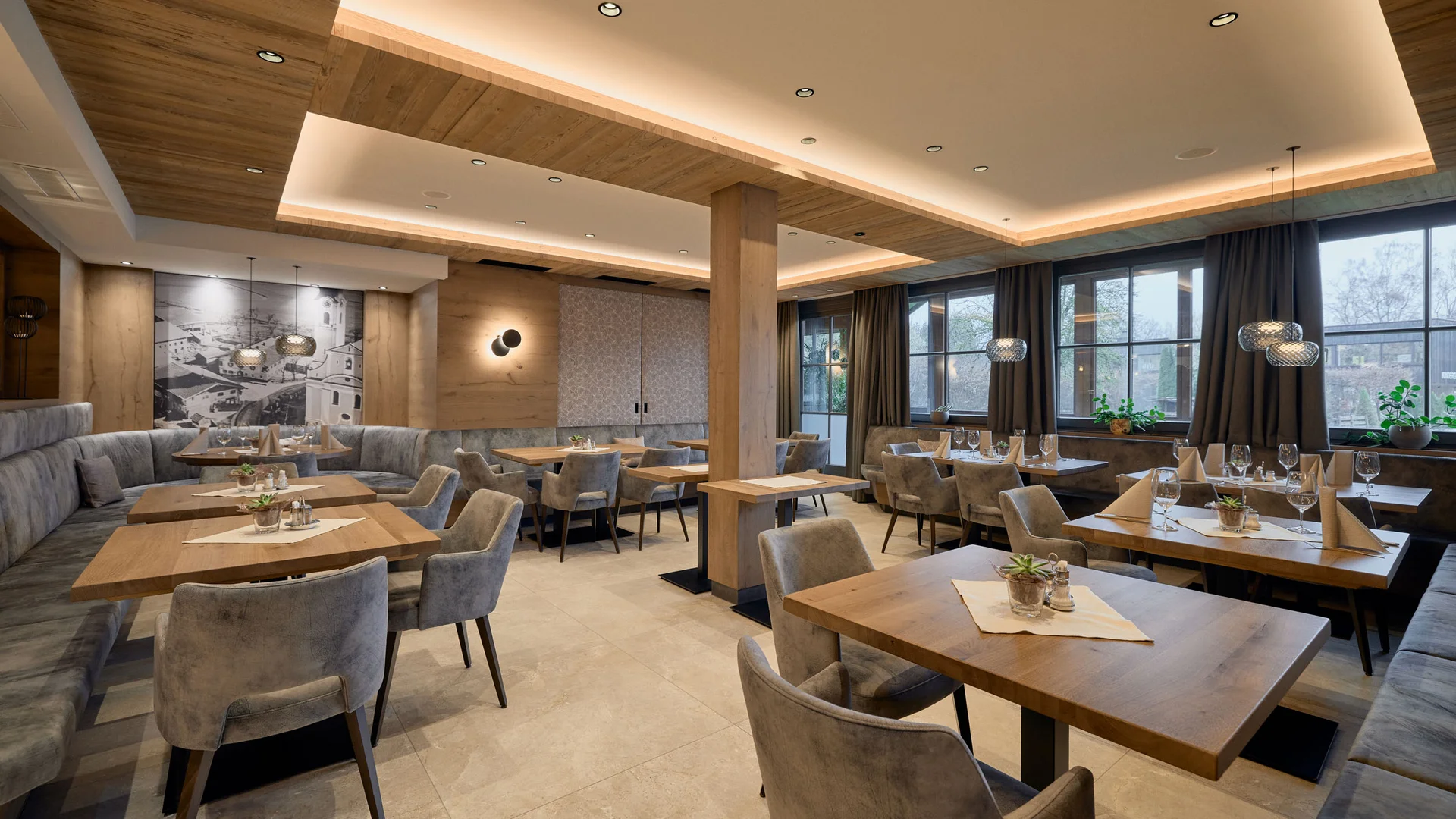 Gasthaus-Hotel Oberwirt **** © Julian Höck Modern restaurant met houten tafels en grijze stoelen in warm licht