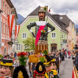 Traditional parade with large puppets and people in historic costumes in a town