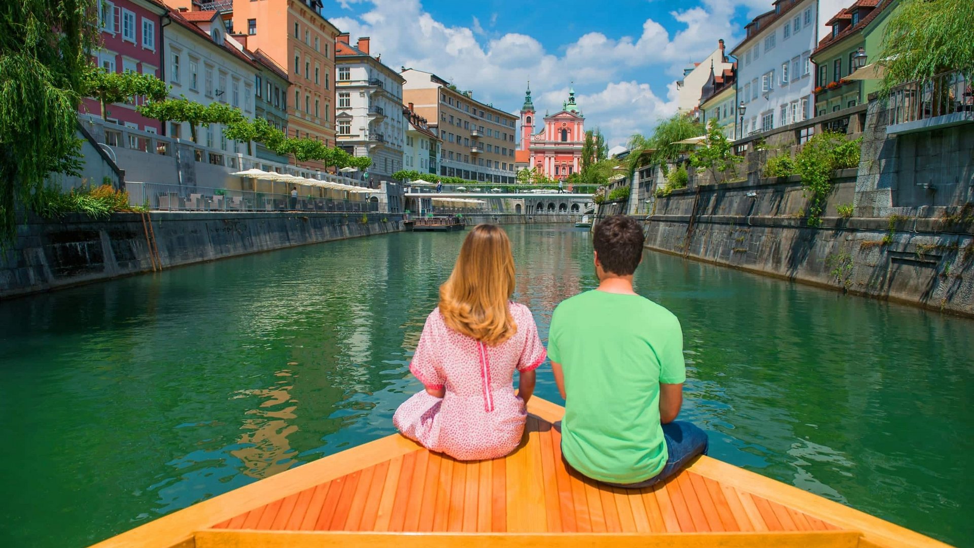 Couple sitting on boat in river with colorful city buildings