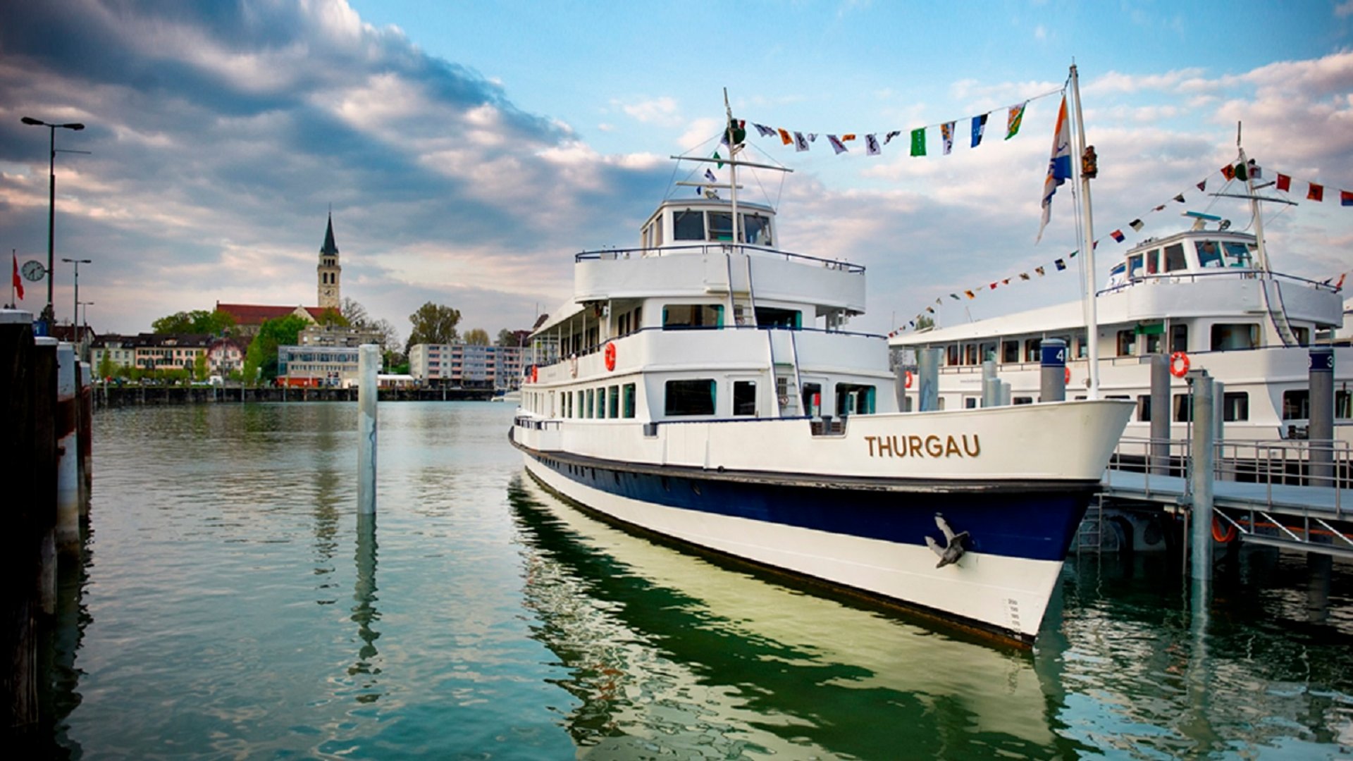 White passenger boats docked in harbor under cloudy sky