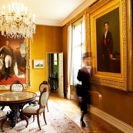 Opulent room with large portrait paintings and antique furniture