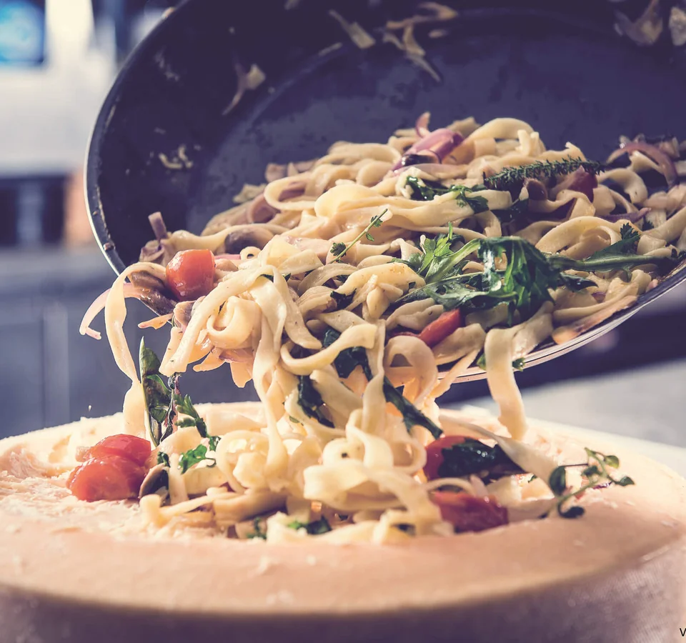 Pasta met groenten geserveerd in een grote kaaswiel