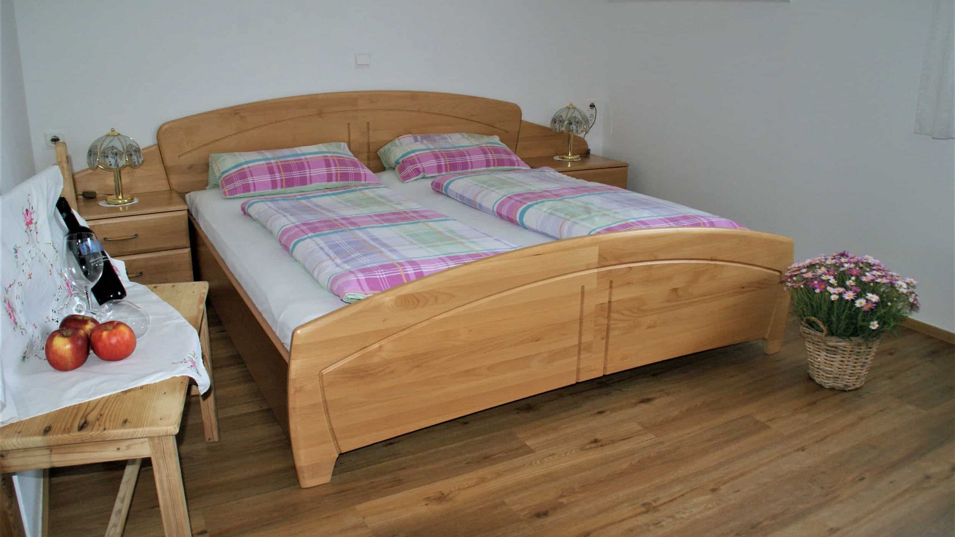 Wooden bed with plaid bedding and nightstands in a simple bedroom