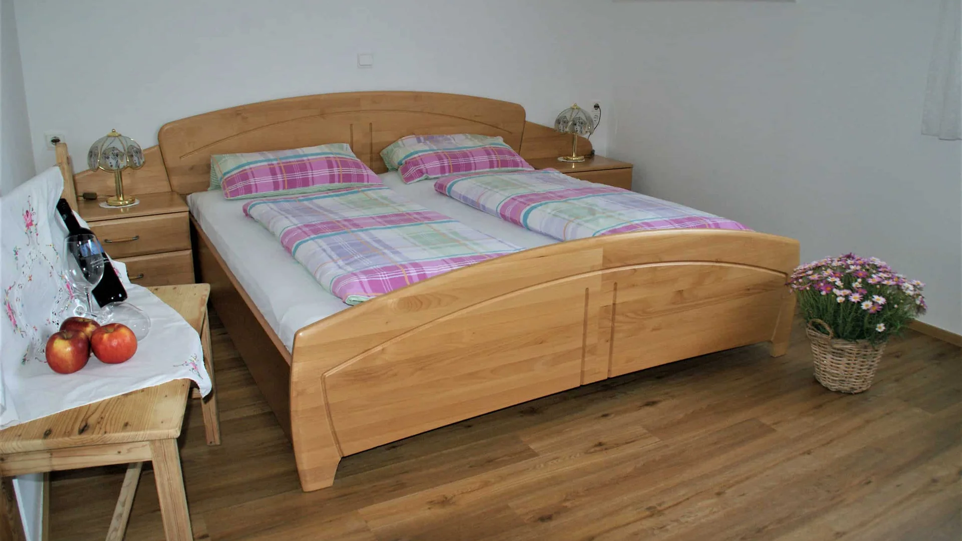 Houten bed met geruite dekens en nachtkastjes in eenvoudige slaapkamer