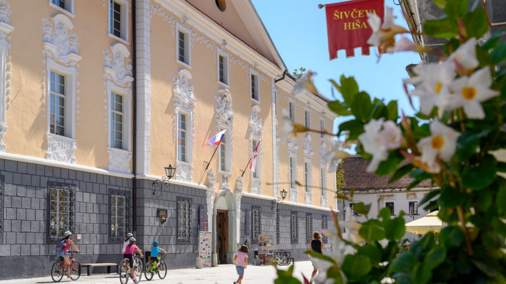 Children biking by baroque building on sunny day
