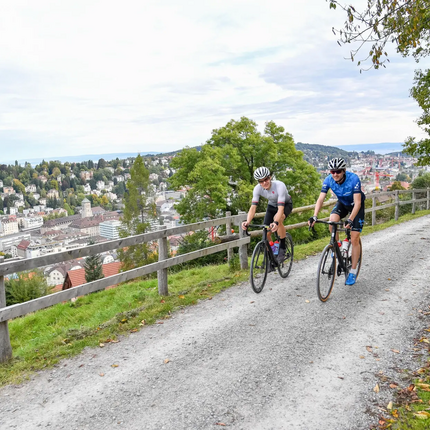 Two cyclists riding on a path with city view in the background