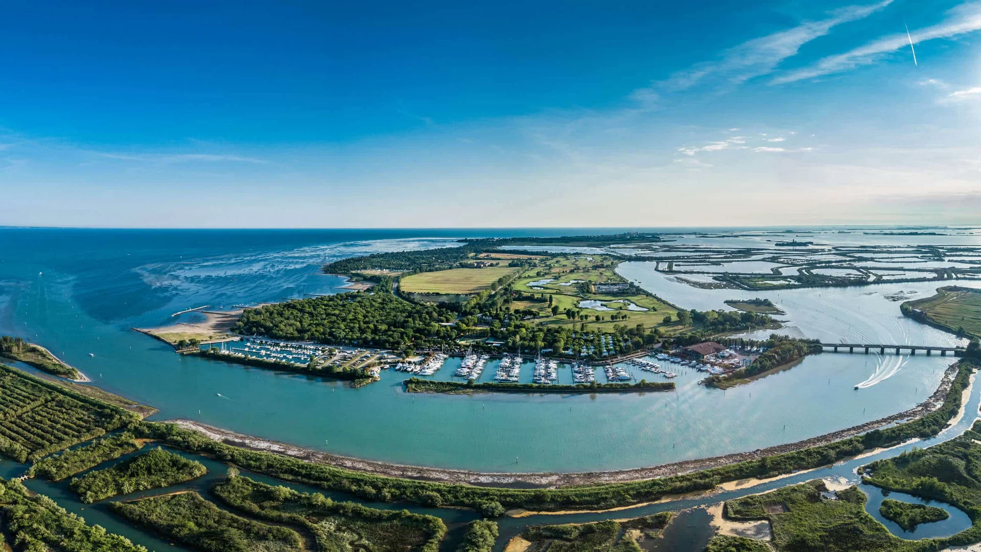 Luchtfoto van kustlijn met haven, riviermonding en beboste gebieden bij zonnige hemel