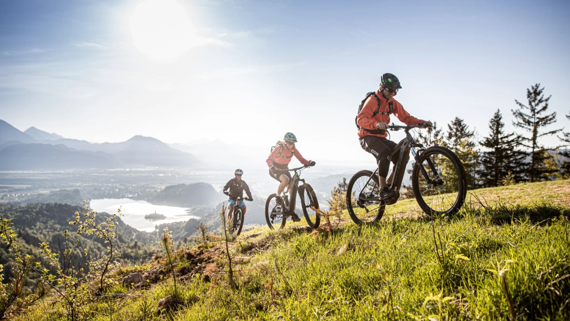 Drie mountainbikers fietsen bergop op een zonnige dag.