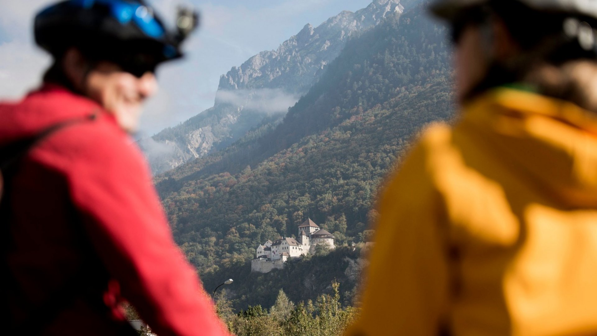 Two cyclists with a mountain and castle in the background